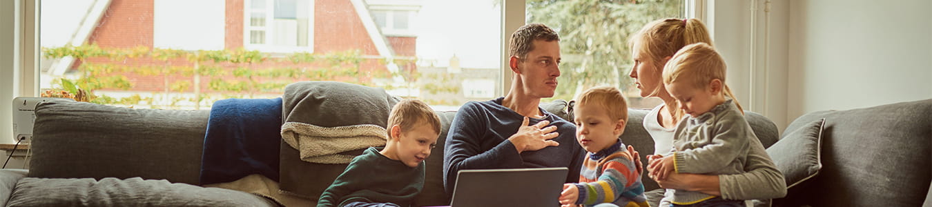 Familie samlet om computeren i sofaen